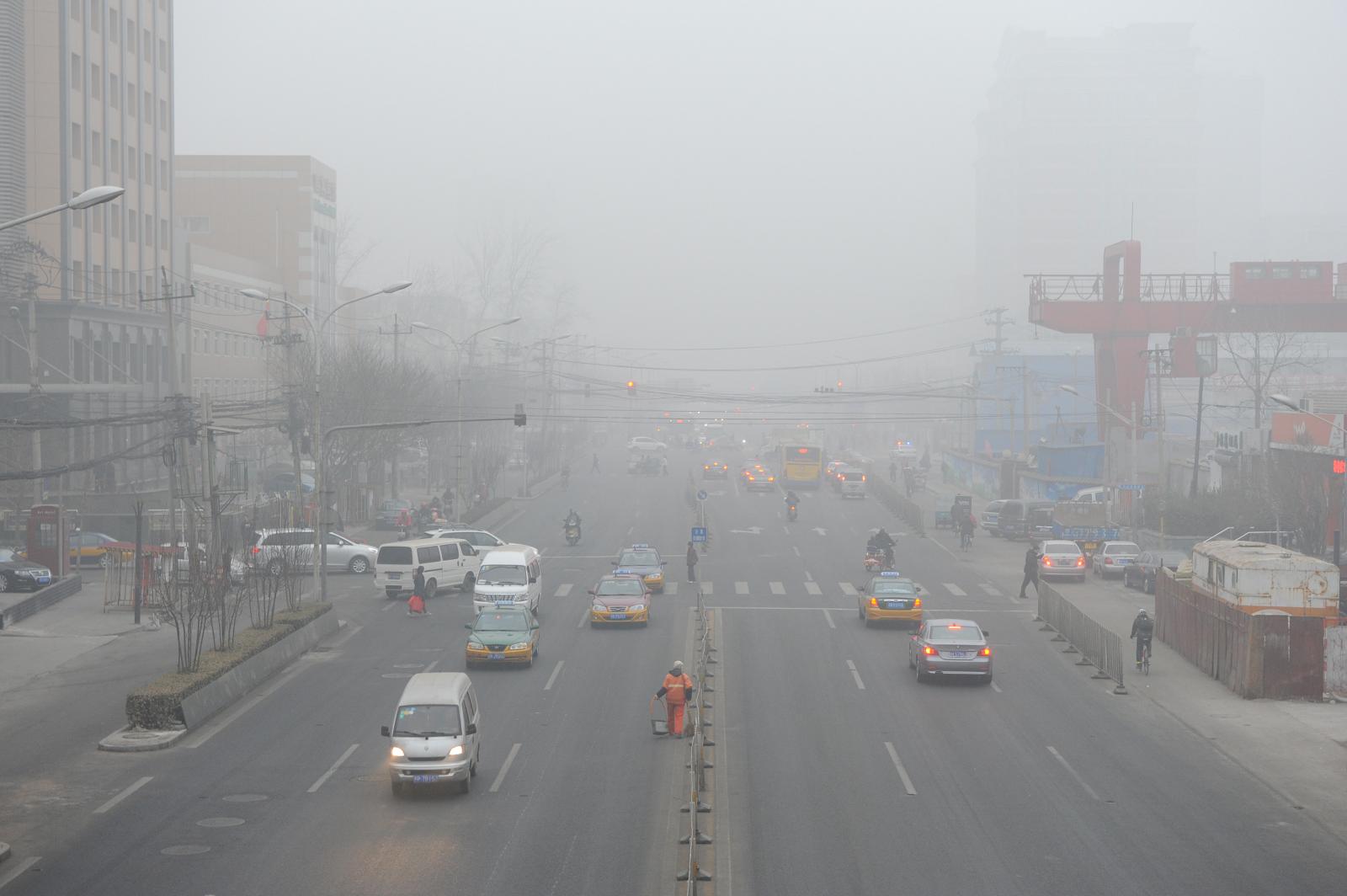 Xe cộ, các tòa nhà cao tầng, cảnh thành phố mờ ảo vì khói bụi ô nhiễm